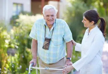 une personne agée en déambulateur avec un docteur en promenade